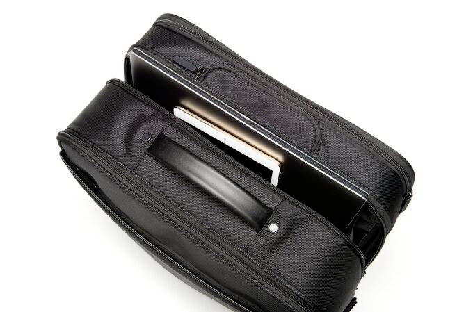 Eine schwarze Tasche mit zwei Reißverschlüssen, in der ein Laptop und ein Tablet verstaut sind.