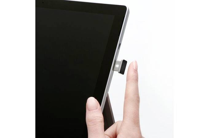Eine Hand steckt ein kleines USB-Gerät in die Seite eines Tablets.