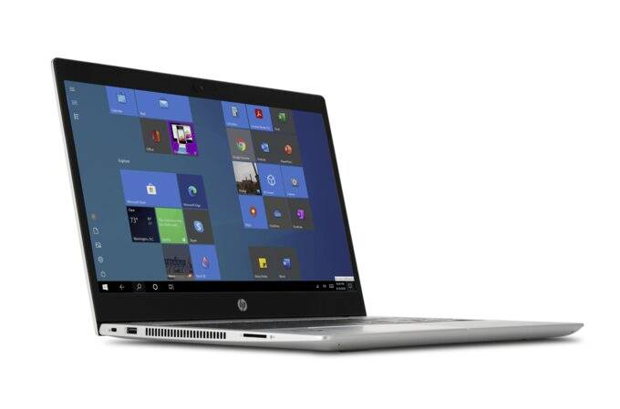Schlanker Laptop mit geöffnetem Windows-Desktop, zahlreiche App-Symbole sichtbar. Designer Gehäuse in Silber, seitliche Ansicht.