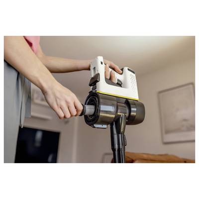 Eine Person setzt einen Filter in einen handgehaltenen Staubsauger ein und veranschaulicht damit einen Wartungsschritt in einem häuslichen Umfeld mit unscharfem Hintergrund.