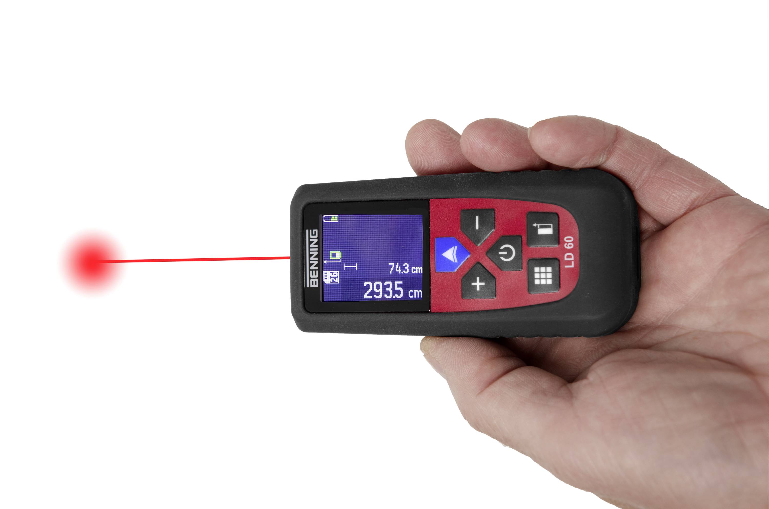 Hand hält ein digitales Laser-Entfernungsmessgerät mit rotem Laserstrahl zielt auf einen Punkt, Anzeige zeigt '74,3 cm' an.