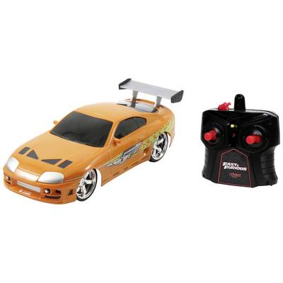 Ein orangefarbenes ferngesteuertes Spielzeugauto mit Spoiler und schwarzen Details neben einer schwarzen Fernsteuerung.