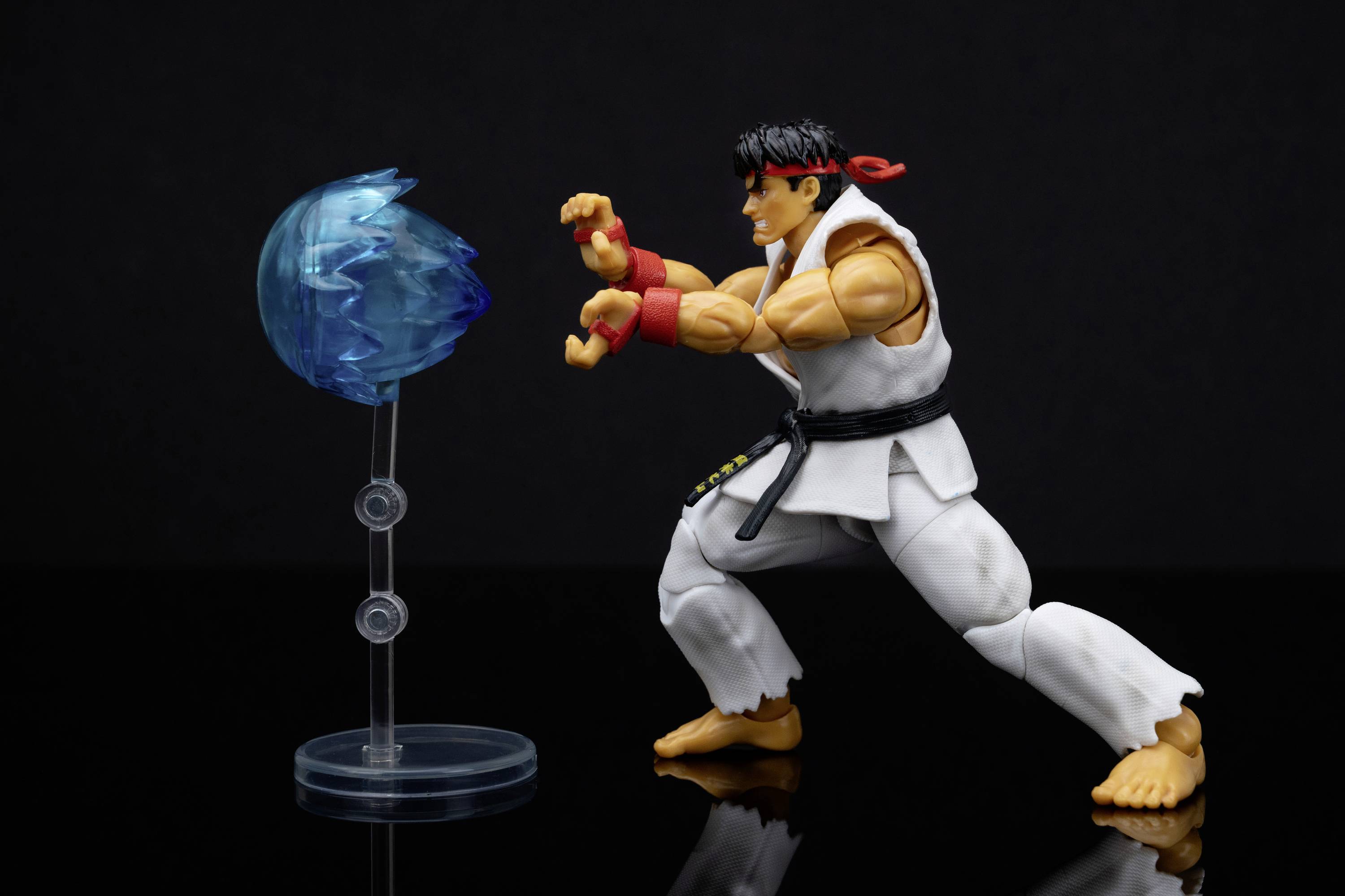 Ein Actionfigur in Kampfanzug führt eine Karate-Technik gegen eine blaue Energie-Kugel aus.