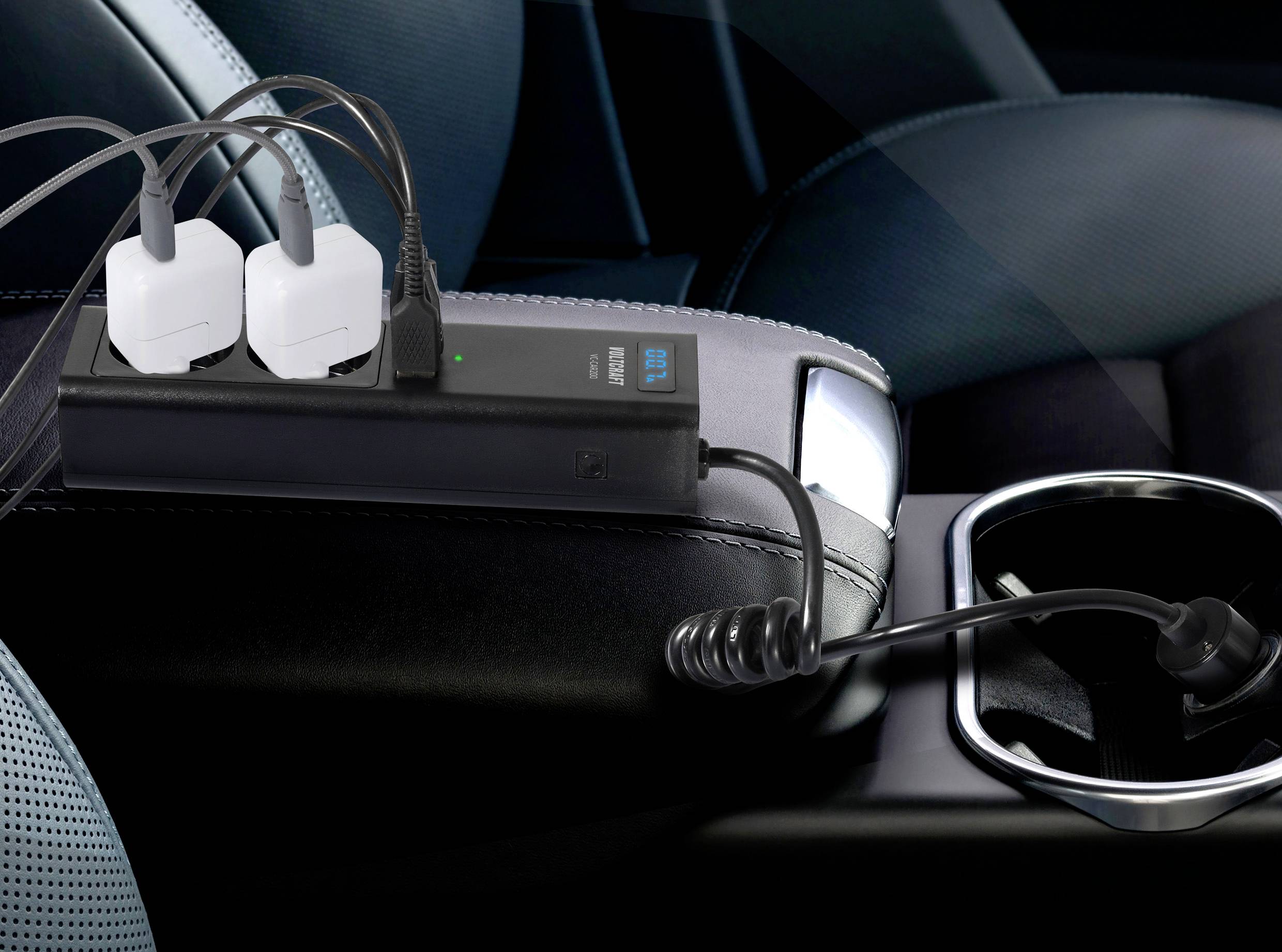 Vier elektronische Geräte sind an eine Mehrfachsteckdose im Auto angeschlossen, die auf einer Armlehne liegt.