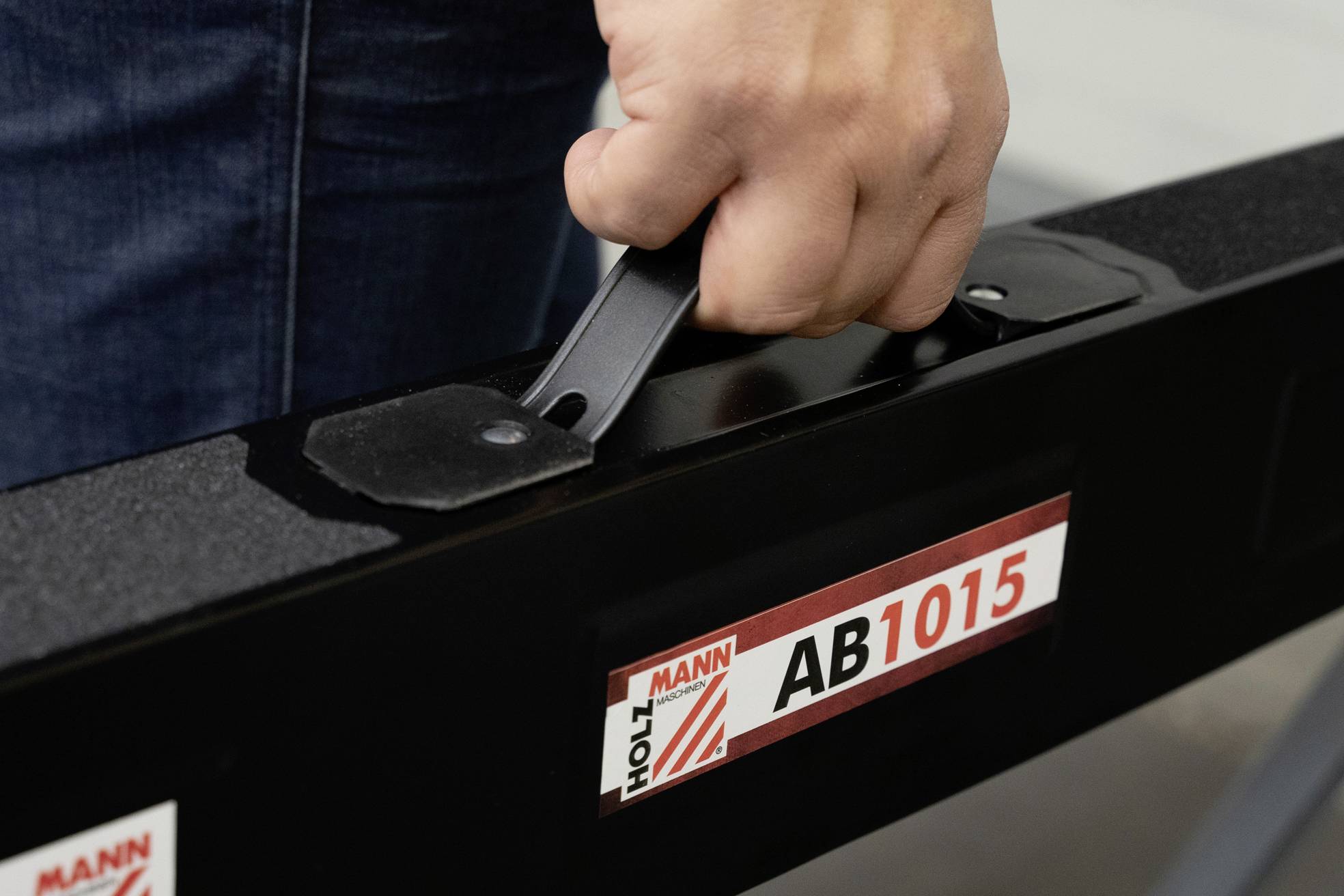 Eine Hand hält den Griff eines schwarzen Werkzeugs mit der Aufschrift 'AB1015'.