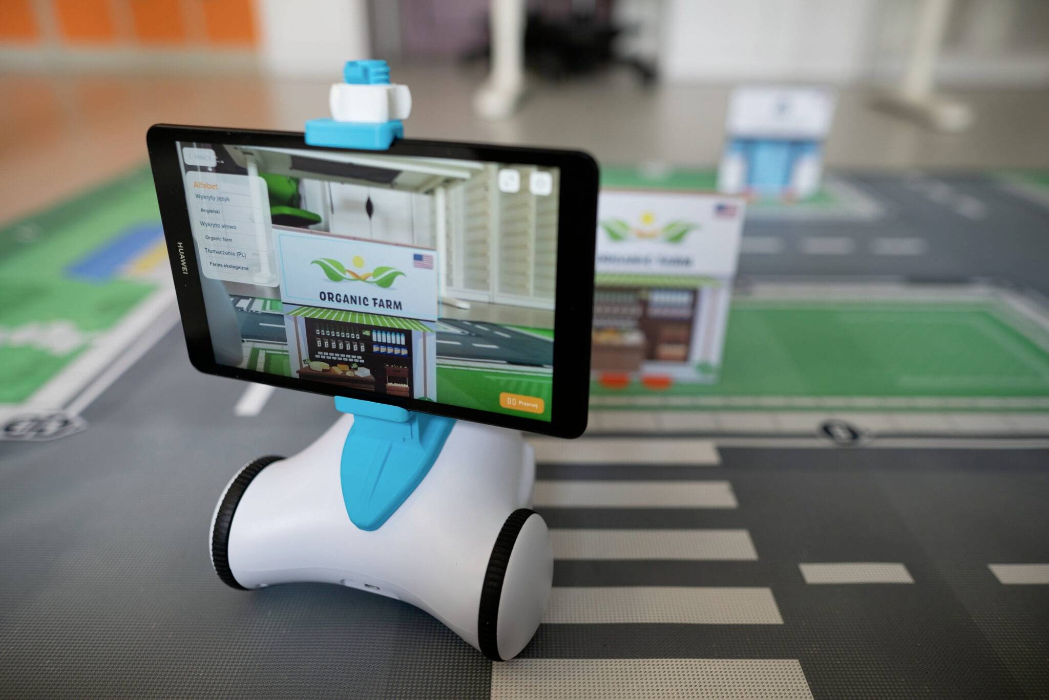 Ein kleiner Roboter mit Tablet, das eine Szene mit einem Schild 'Organic Farm' zeigt, steht auf einer Straßenkarte.