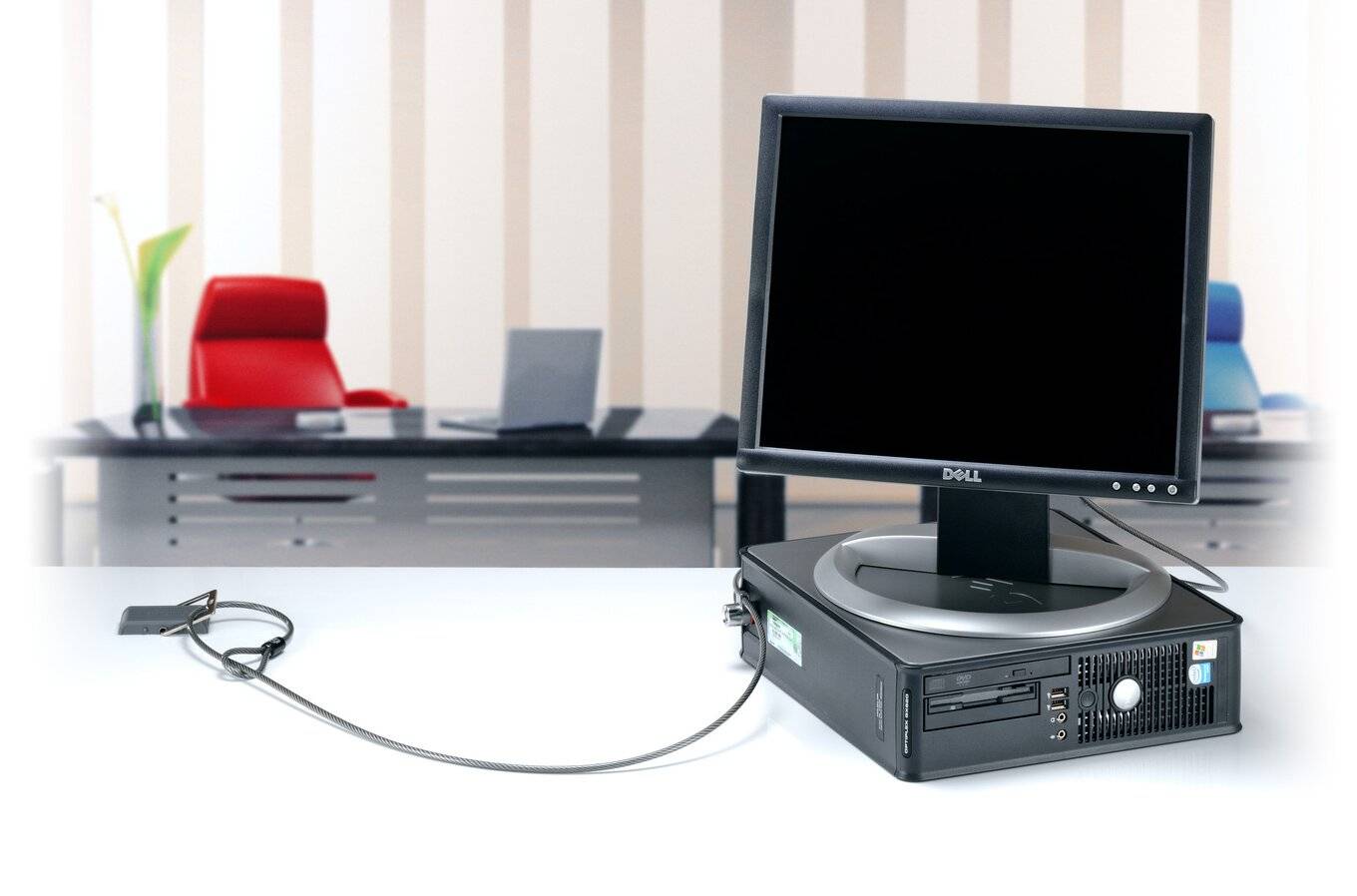 Ein Desktop-Computer mit Monitor, im Vordergrund einer modernen Büroumgebung mit Schreibtischen und Stühlen im Hintergrund.