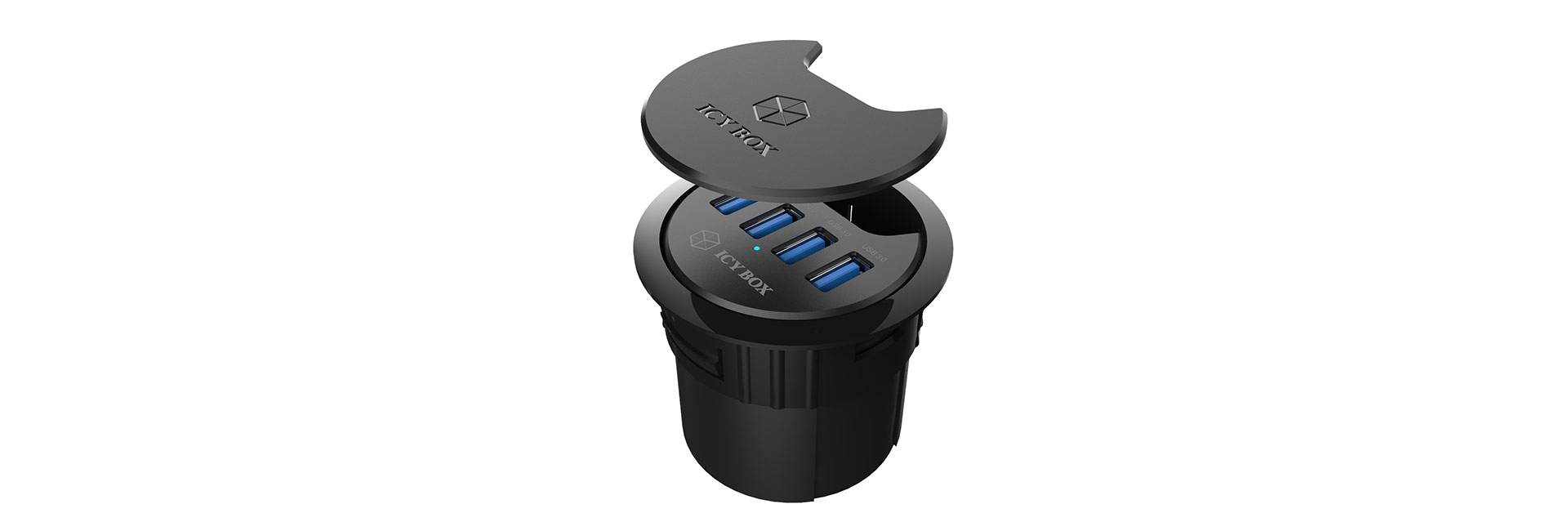 Schwarze runde Einbau-Steckdose mit vier USB-Anschlüssen und abnehmbarem Deckel von oben betrachtet.