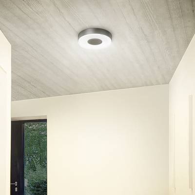 Moderne Deckenleuchte strahlt warmes Licht in einem minimalistischen Raum aus, der eine große Glastür mit Blick ins Grüne hat.