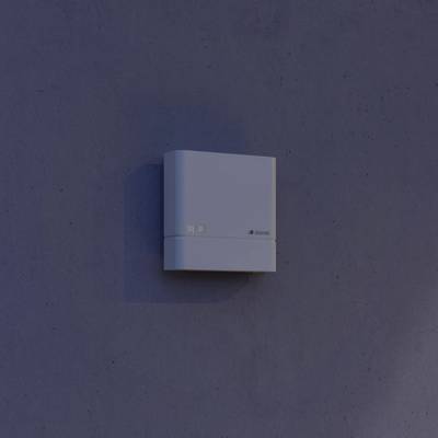 Ein weißer, quadratischer Kasten eines elektronischen Geräts ist an einer blaugrauen Wand montiert. Das Gerät hat ein schlichtes Design.