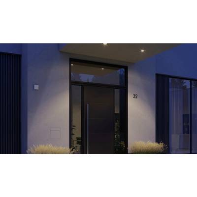 Moderne Eingangstür eines Hauses bei Dämmerung, beleuchtet durch drei Deckenspots. Hausnummer '32' an der Wand neben der Tür.