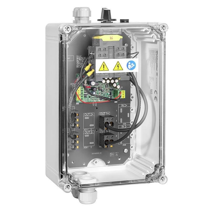 Ein Gehäuse aus klarem Kunststoff zeigt elektronische Platinen mit Kabeln und Anschlüssen. Zwei Warnsymbole sind sichtbar.