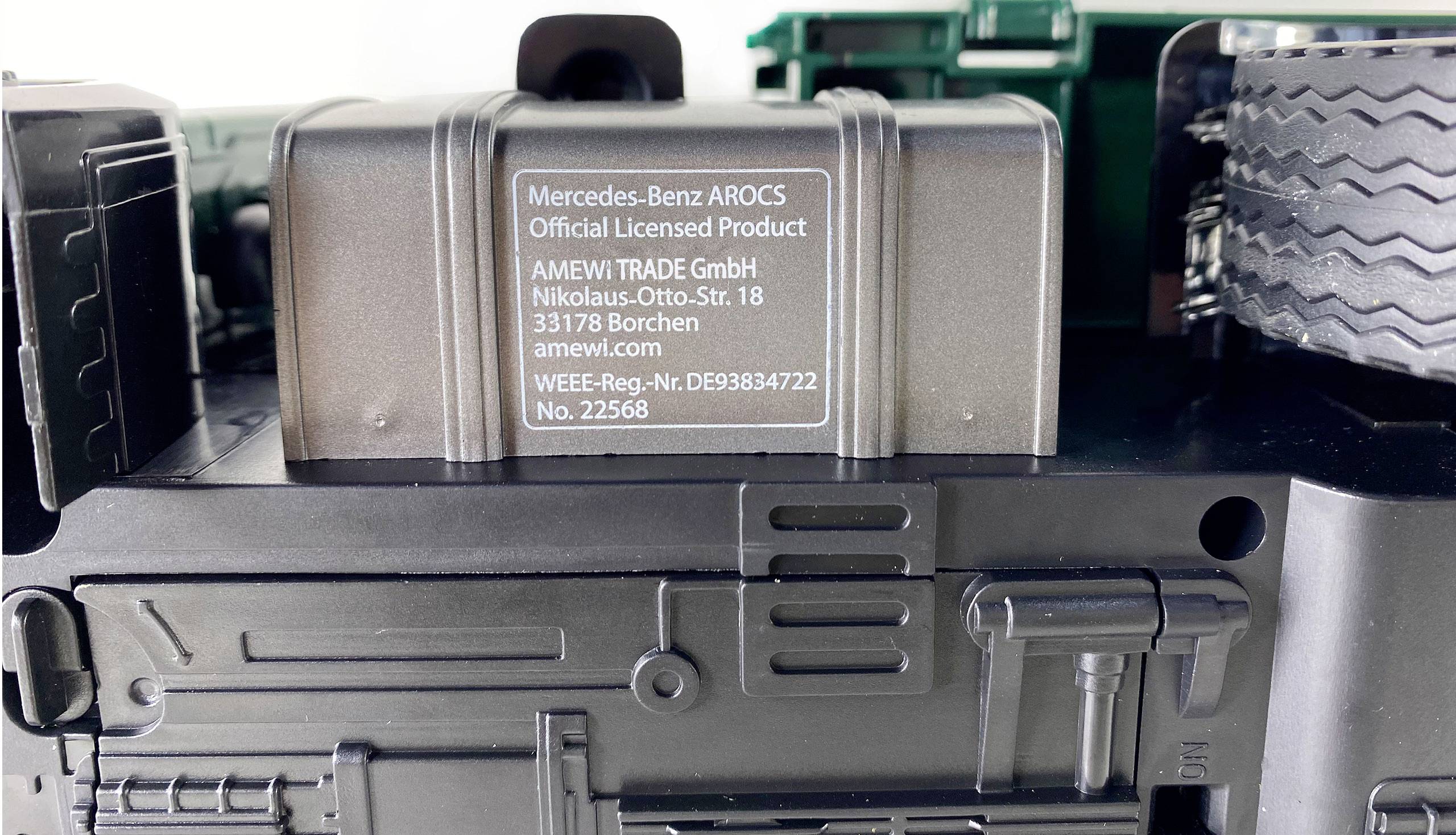 Etikett auf einem Modell-LKW: 'Mercedes-Benz AROCS Official Licensed Product.' Hersteller: AMEWI TRADE GmbH, Adresse, Seriennummer.