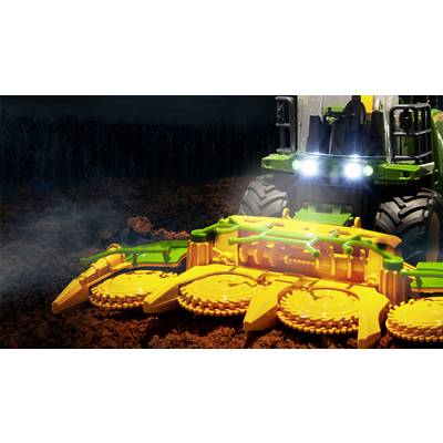 Traktor auf einem Feld bei Nacht mit leuchtenden Scheinwerfern, Bewirtschaftung der Erde mit einem großen, gelben Anbaugerät im Vordergrund.