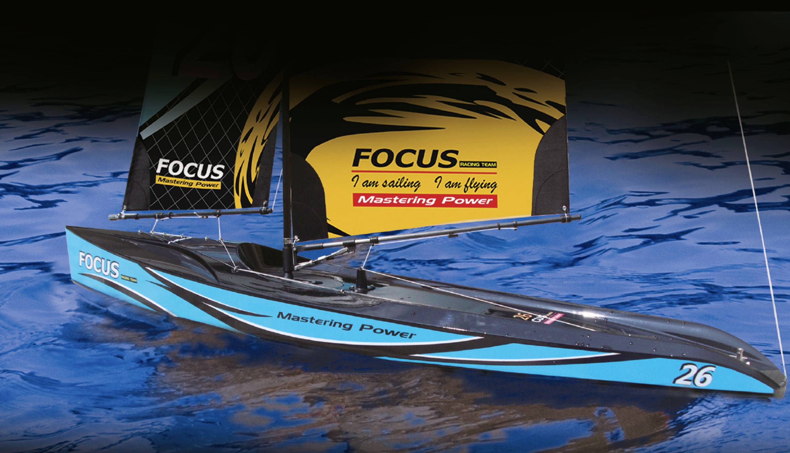 Ein Modell-Segelboot mit blauen und schwarzen Segeln trägt die Aufschrift 'Mastering Power'. Es schwimmt auf blauem Wasser.