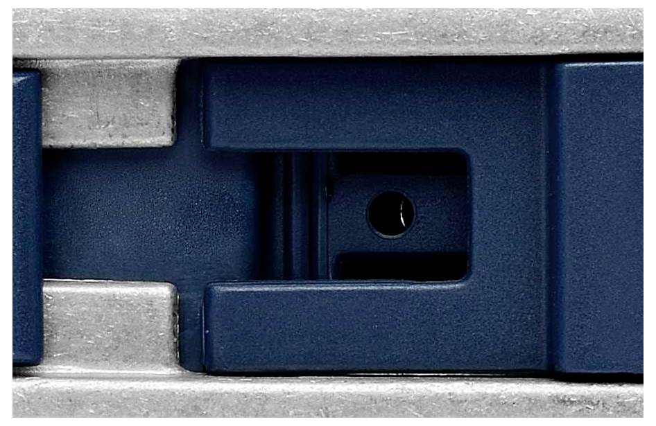 Nahaufnahme eines blauen Metallverschlusses oder -clips, montiert auf einer silbernen Basis mit sichtbaren Kanten.