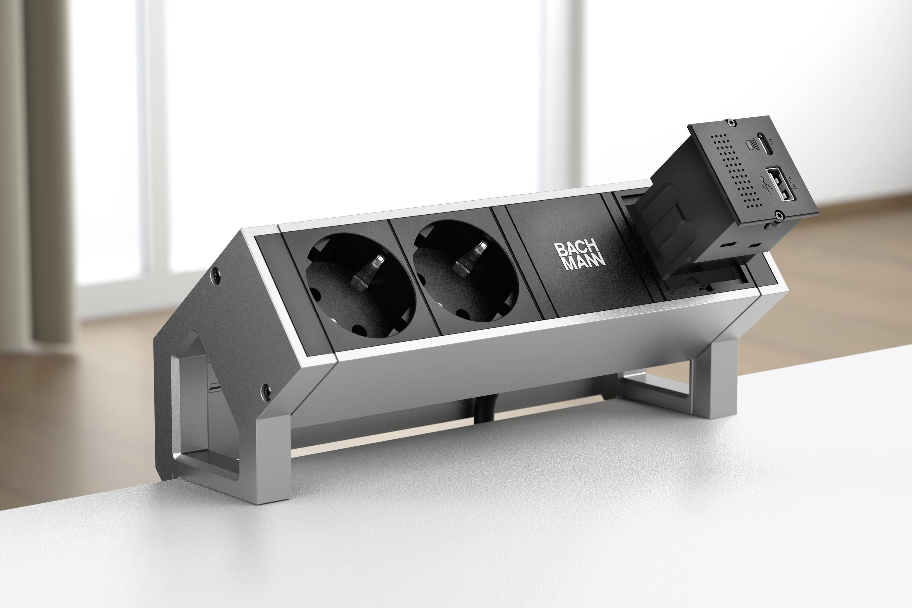 Steckdosenleiste mit zwei Steckdosen und einem USB-Anschluss, montiert auf einem Tisch. Hintergrund ist ein Raum mit natürlichem Licht.