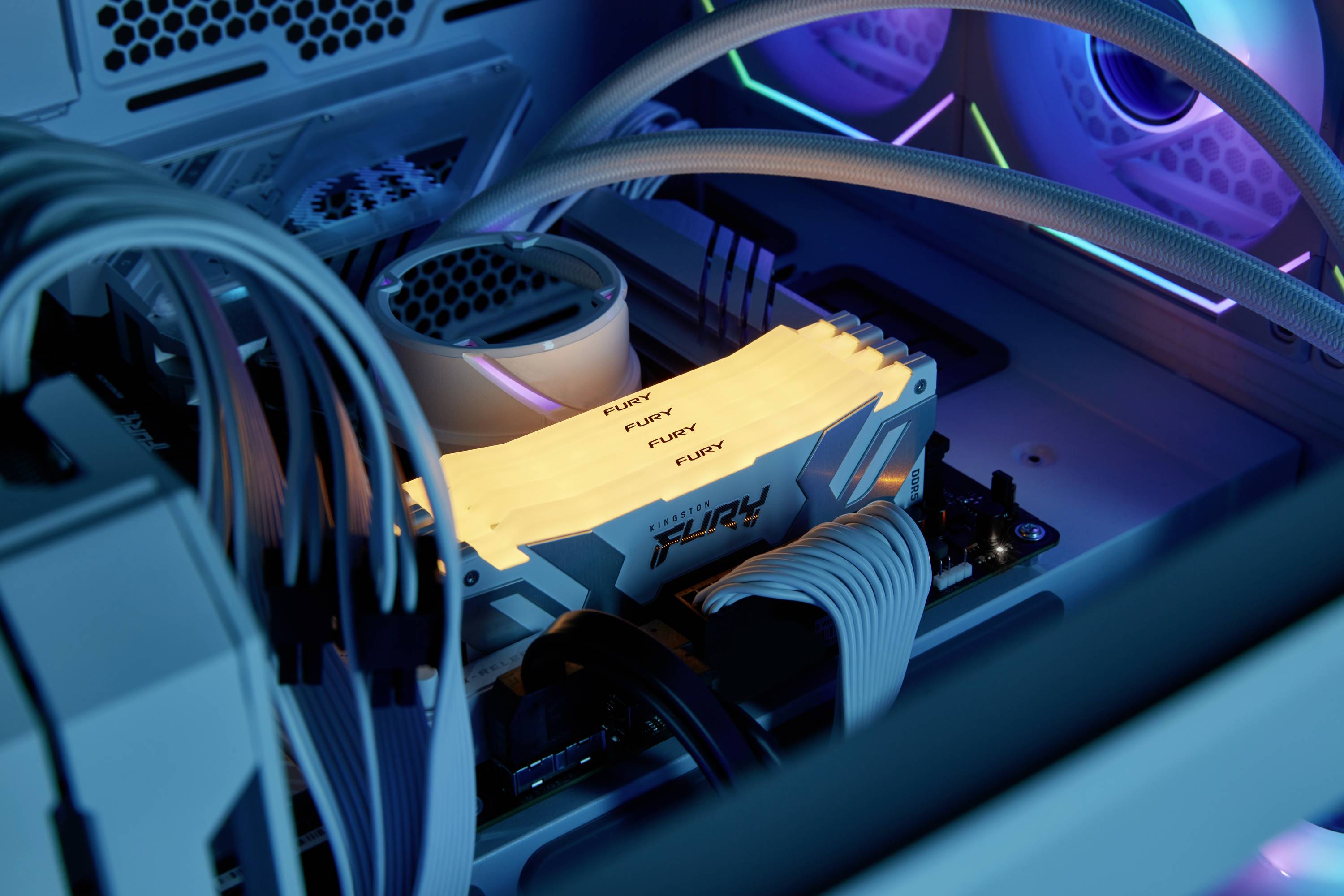 Leuchtende RAM-Module in einem Computergehäuse, umgeben von weißen Kabeln und Lüftern, erzeugen ein dynamisches, technisches Ambiente.