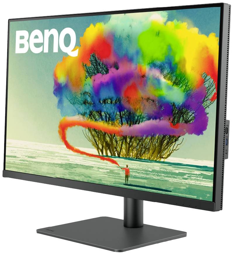 'BenQ'-Monitor zeigt farbenfrohes Bild eines Baumes mit kunterbunten Wolken. Eine Person steht mit einem Spray in der Hand davor.