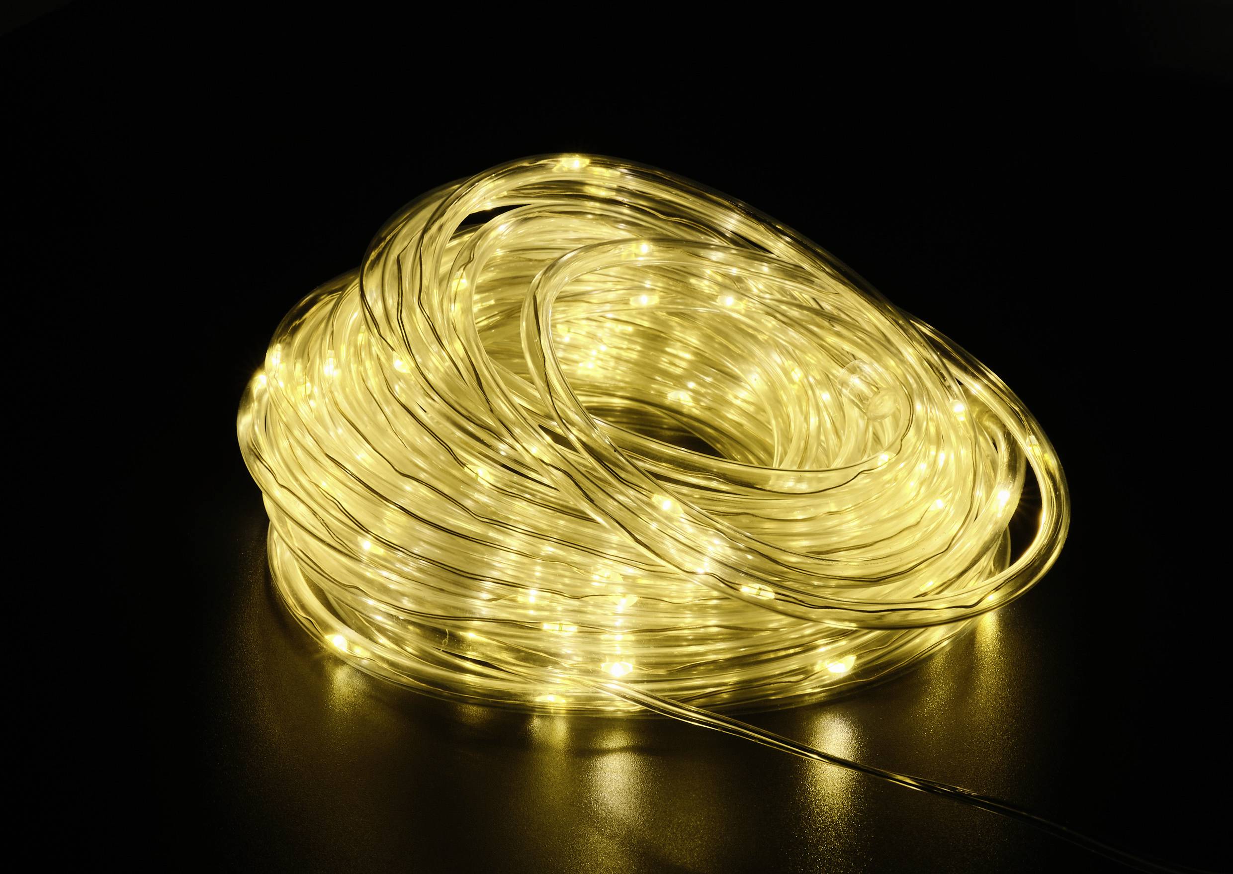 Ein zusammengerollter LED-Lichtschlauch, der warmes gelbes Licht ausstrahlt, liegt auf einer dunklen Oberfläche.