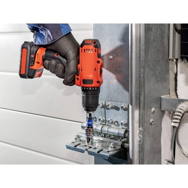 Eine Person verwendet einen orangefarbenen kabellosen Akkuschrauber, um eine Metalltorhalterung einer Garage zu befestigen und trägt dabei Arbeitshandschuhe, was die Heimwerker-Wartungsarbeiten unterstreicht.