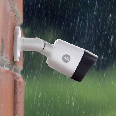 Überwachungskamera an einer Wand montiert, filmt bei Regenwetter.