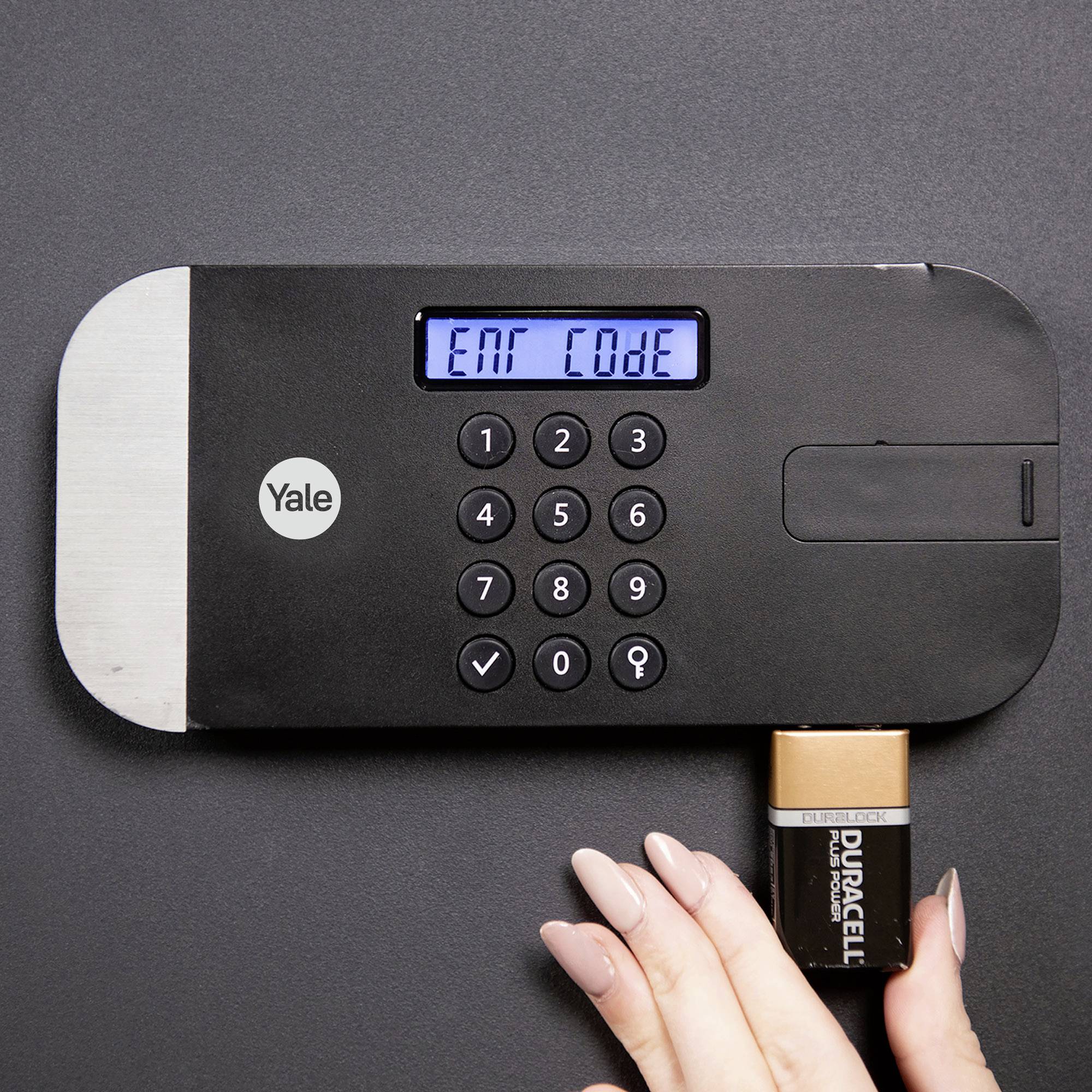 Ein Zahlenschloss mit digitalem Display zeigt 'Ent Code' an, während eine Hand eine Batterie einlegt.