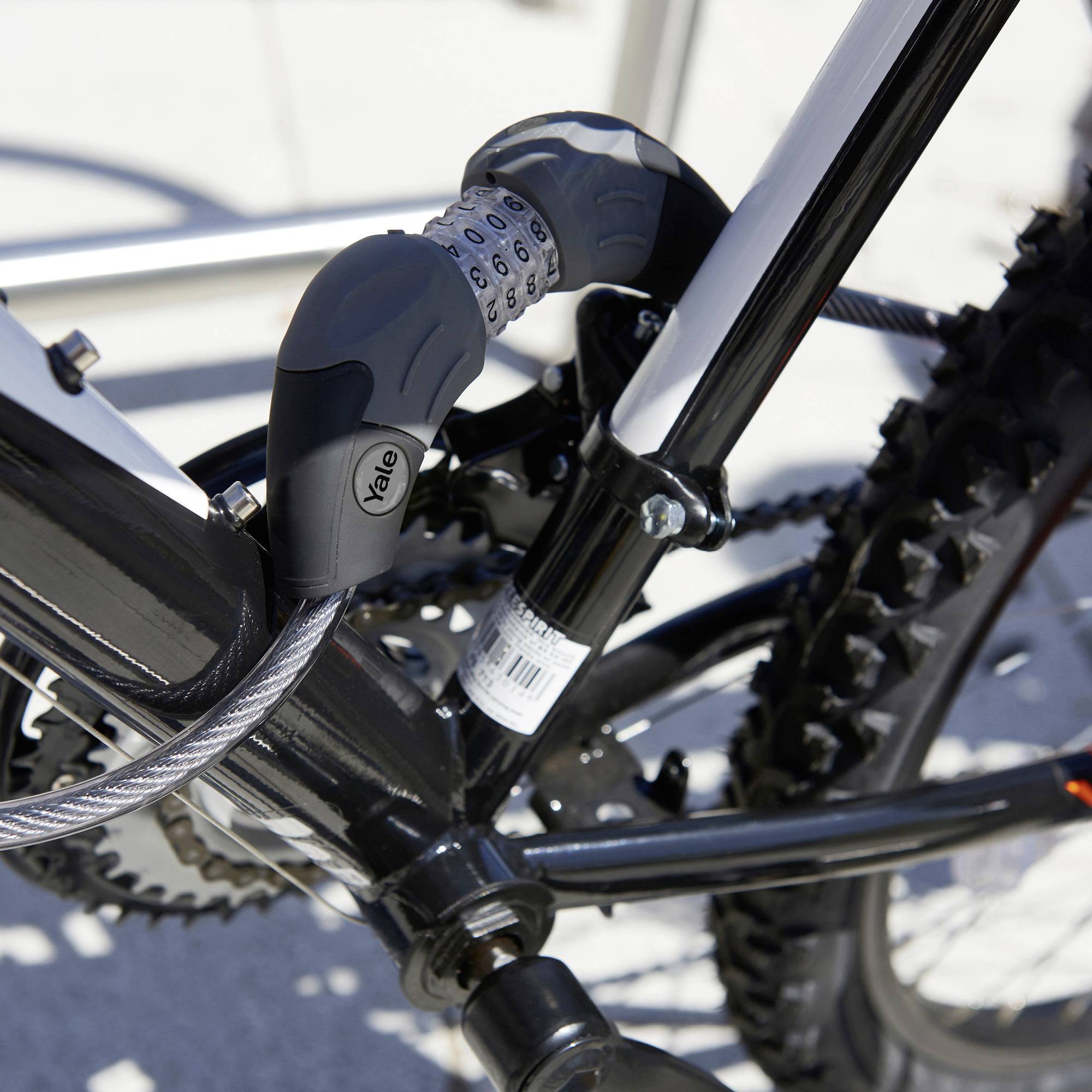 Ein Fahrrad mit schwarzem Rahmen ist mit einem schwarzen Sicherheitsschloss an einem Fahrradständer befestigt.