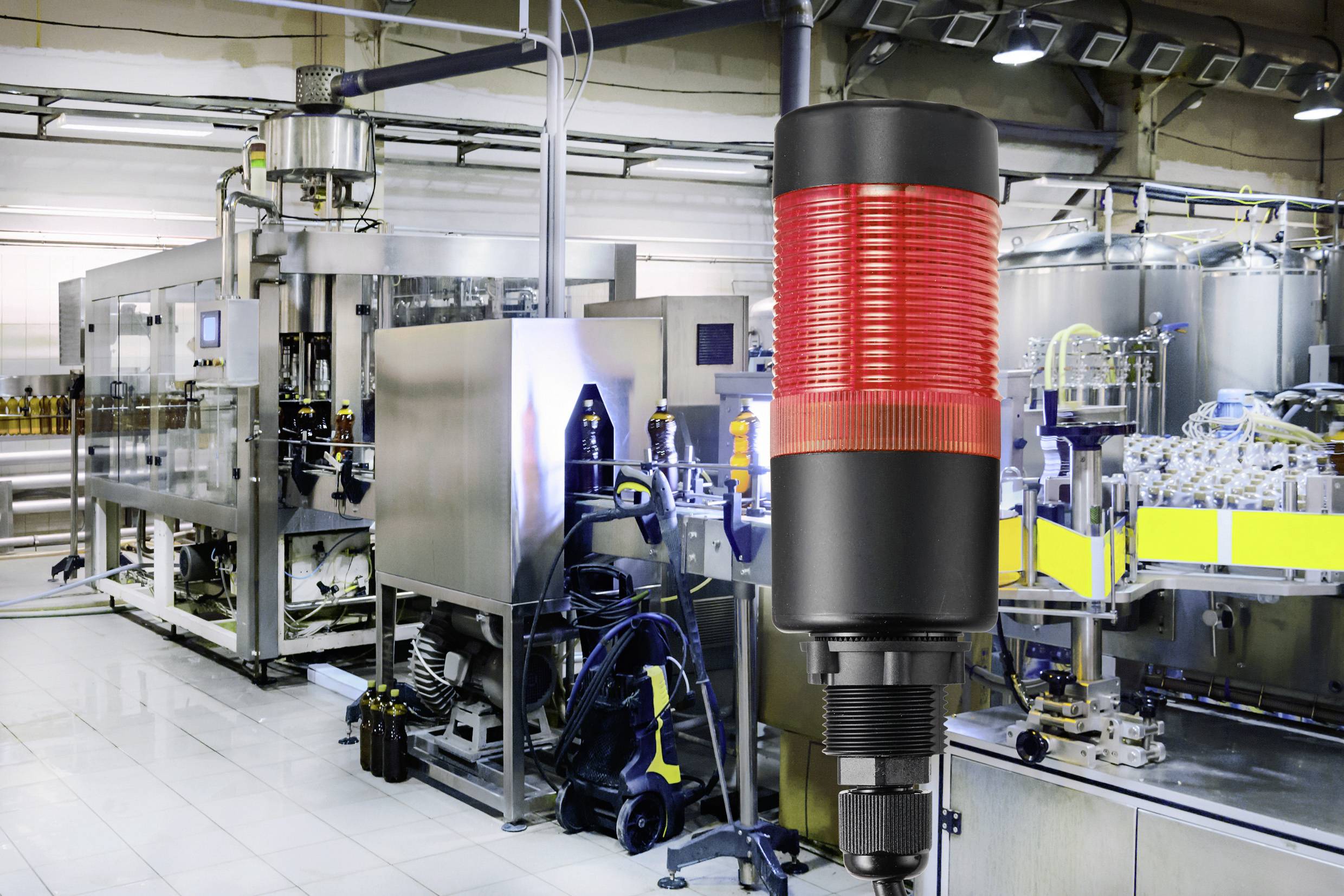 In einer Produktionsanlage leuchtet ein rotes Warnsignal vor Maschinen, was auf einen möglichen Stopp oder Fehler hinweist.