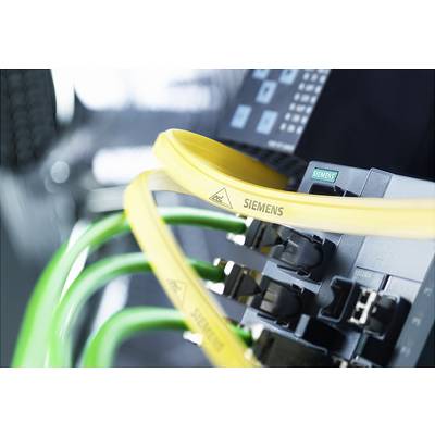 Ein Netzwerkrouter mit gelben und grünen Kabeln, die in Steckplätze eingesteckt sind. Hintergrund unscharf, Fokus auf die Kabel.