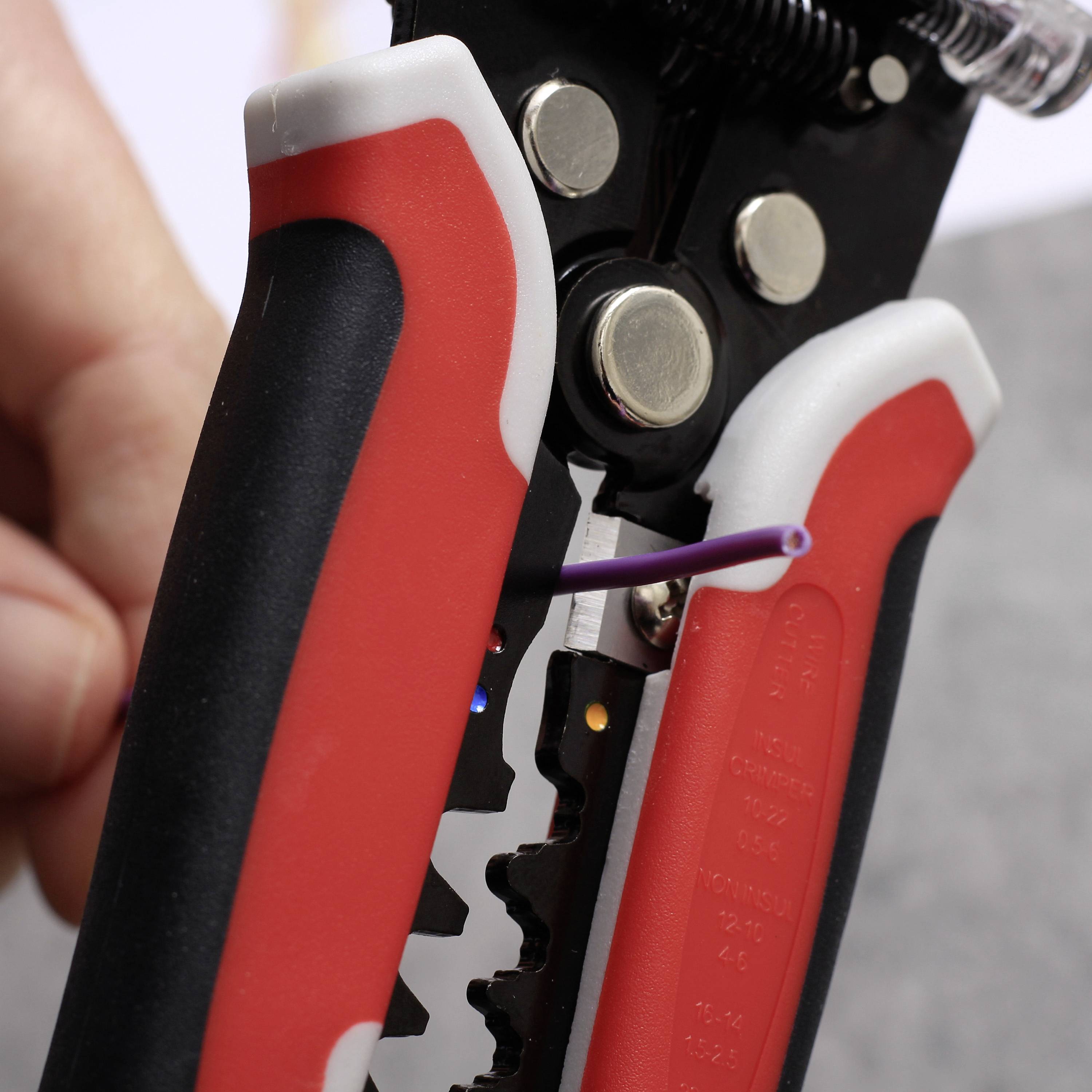 Eine Hand hält einen Abisolierzange, die ein lila Kabel abisoliert. Nahaufnahme, Fokus auf die Zange und das Kabel.