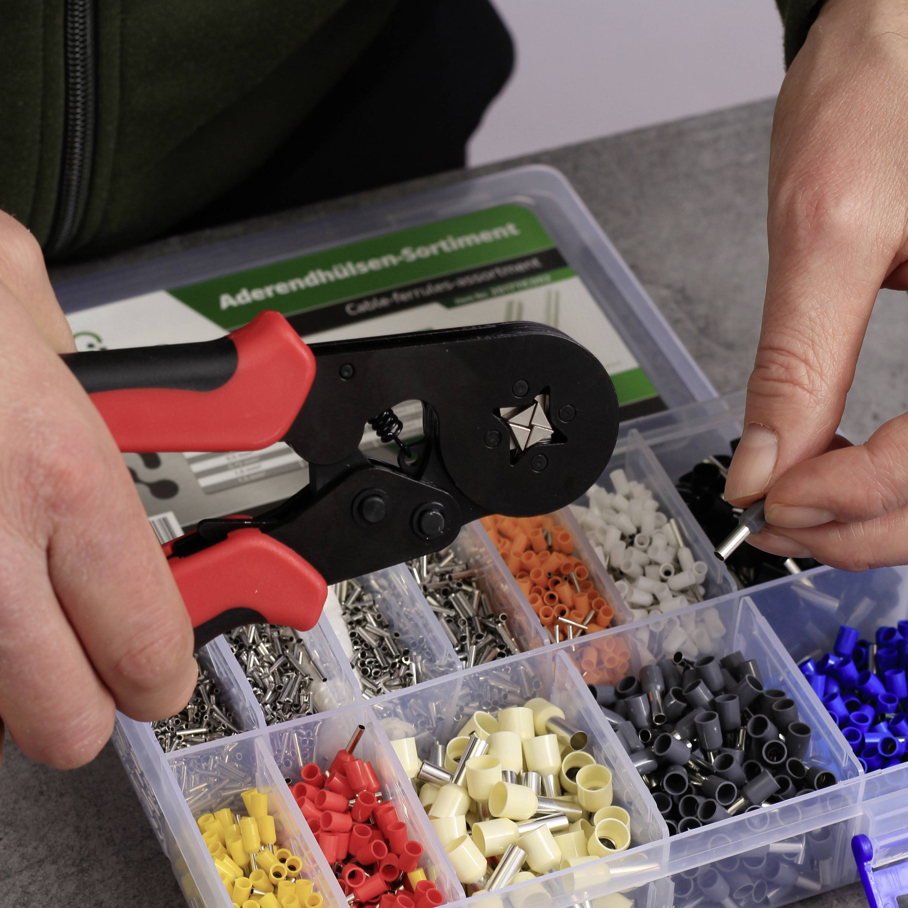 'Hand crimping tool zum Crimpen von Kabeln mit Crimpeinsätzen in verschiedenen Farben und Größen. Nahaufnahme auf einem Tisch.'