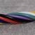 Mehrfarbige, gedrehte Kabel auf grauem Hintergrund. Kabel in Rot, Schwarz, Lila, Grün, und Weiß.