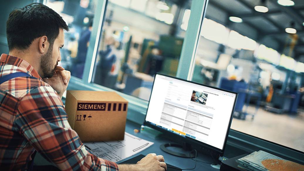 Mann in Werkstatt sitzt am Schreibtisch vor einem Computerbildschirm. Neben ihm ein Paket mit 'Siemens'-Logo. Produktionshalle im Hintergrund.