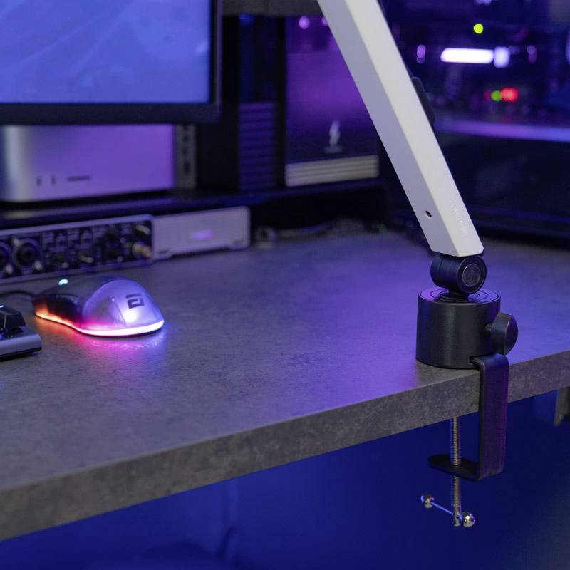 'Schreibtisch mit Computer, Monitor, beleuchteter Maus und Schreibtischlampe, alles in einer modernen Büroumgebung.'