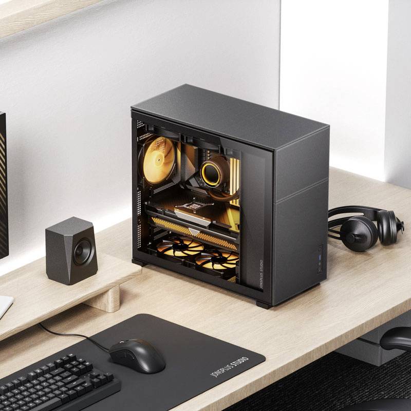 Ein Computer mit transparentem Gehäuse zeigt leuchtende, orangefarbene Komponenten im Inneren. Daneben befinden sich Kopfhörer und Lautsprecher auf einem Schreibtisch.