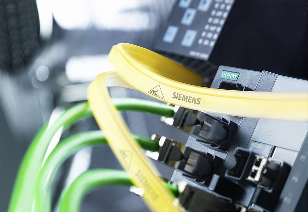 Netzwerkkabel sind an einem Siemens-Gerät angeschlossen. Gelbes und grünes Kabel, unscharfer Hintergrund, Fokus auf Technik.