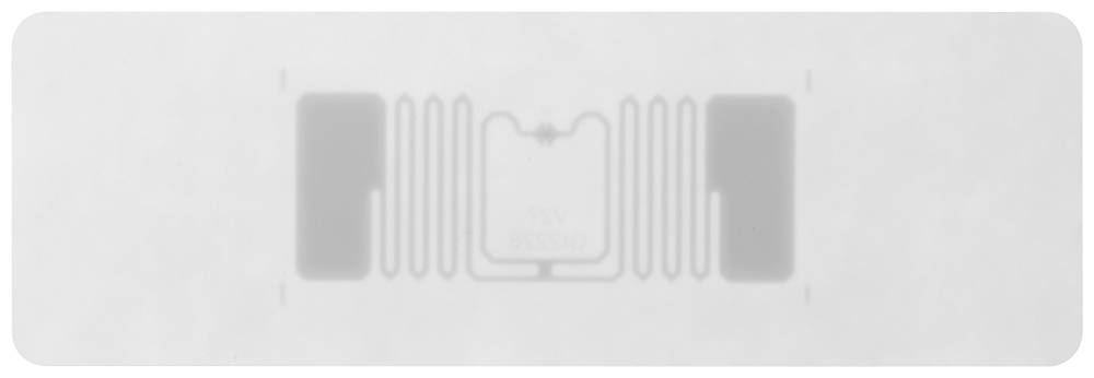 Ein RFID-Etikett auf weißem Hintergrund. Es zeigt eine schlanke, rechteckige Form mit Antennenstruktur und einem kleinen Chip in der Mitte.
