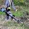 Eine Person in Schutzkleidung benutzt einen Motorsensen-Trimmer, um hohes Gras und Unkraut auf einem Feld zu schneiden.
