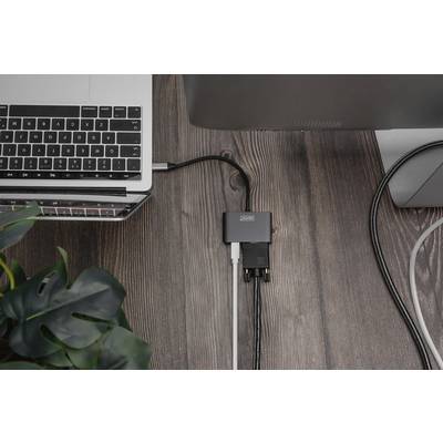 Ein Laptop und ein Monitor sind über einen USB-Hub verbunden, auf einem Holztisch. Links unten ist eine Pflanze sichtbar.