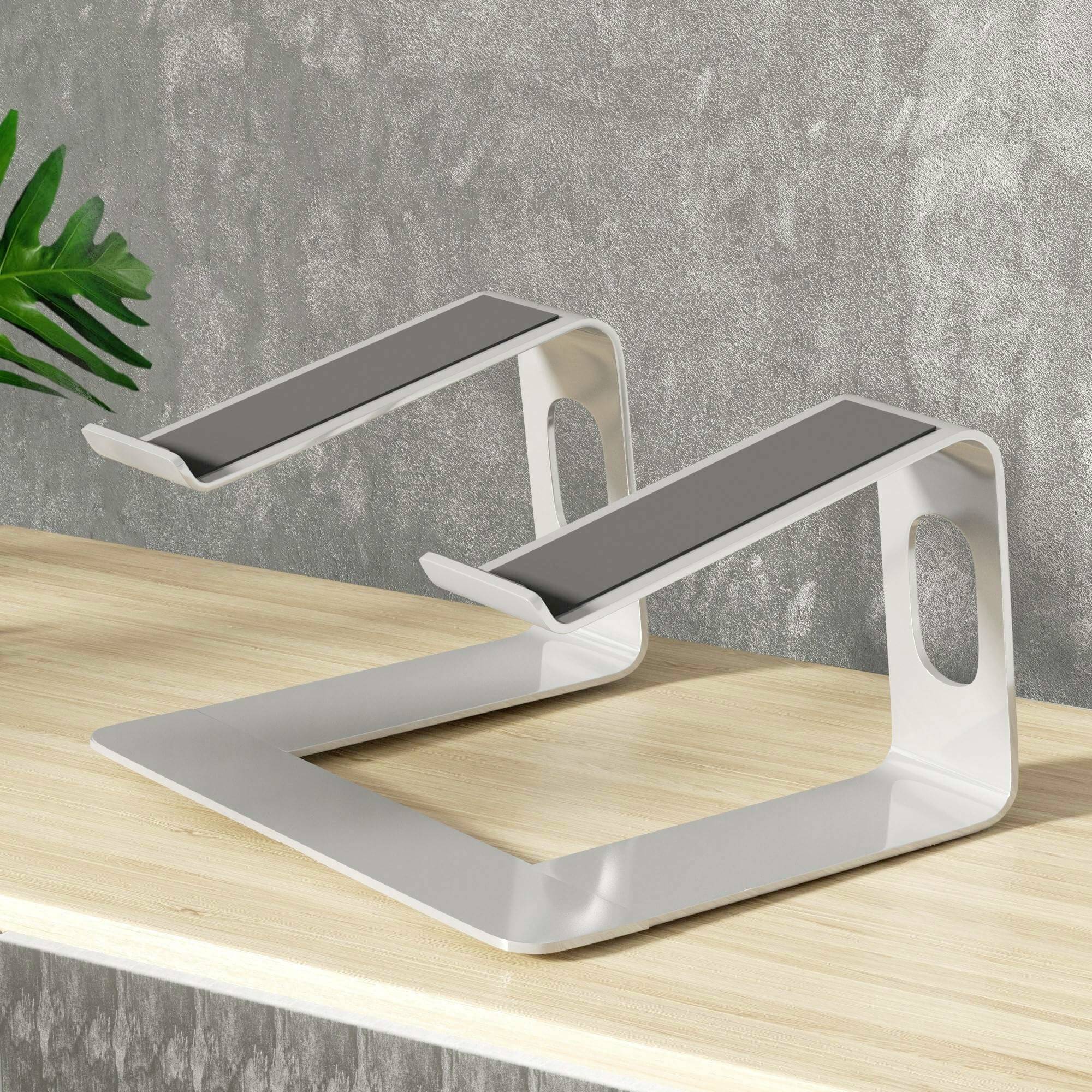 Laptopständer aus Metall auf einem Holztisch, mit schwarzer rutschfester Oberfläche, geeignet zur Erhöhung von Laptops für ergonomisches Arbeiten.