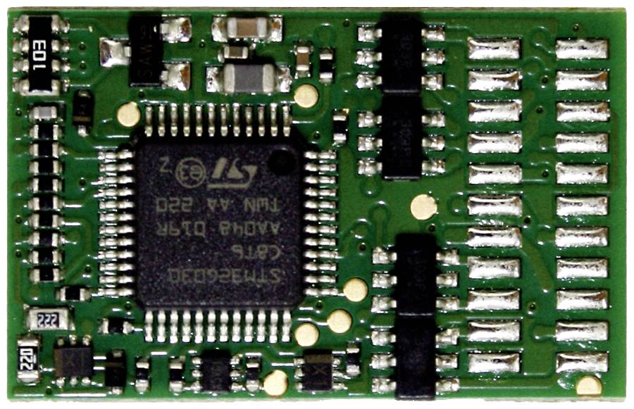 Ein grünes Elektronikbauteil mit zahlreichen Anschlüssen und einem zentralen Mikrochip, beschriftet mit technischen Details.