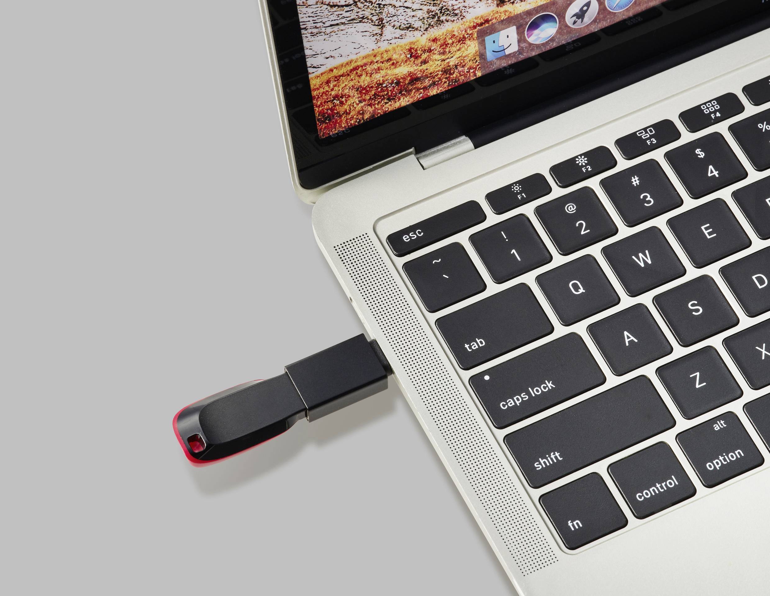 Ein USB-Stick ist in den USB-Anschluss eines Laptops eingesteckt. Der Laptop zeigt einen teilweise sichtbaren Bildschirm mit Icons an.