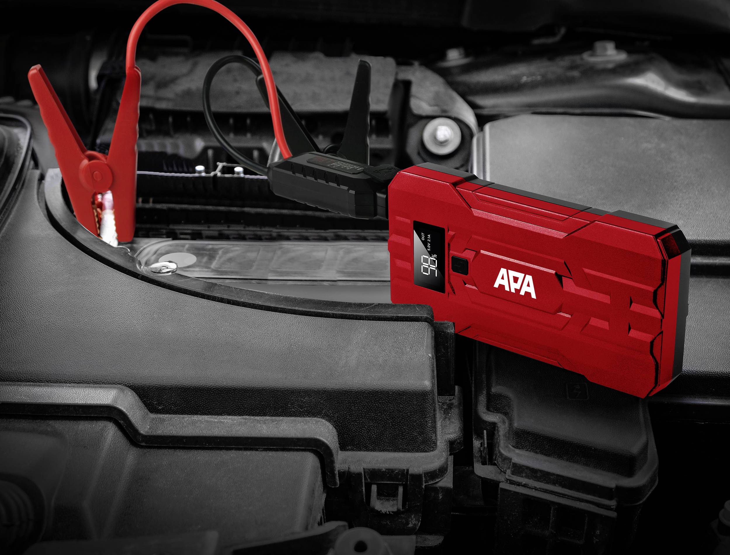 Ein rotes Startgerät ist an die Batterie eines Autos angeschlossen. Es dient zum Überbrücken und Starten eines Fahrzeugs.