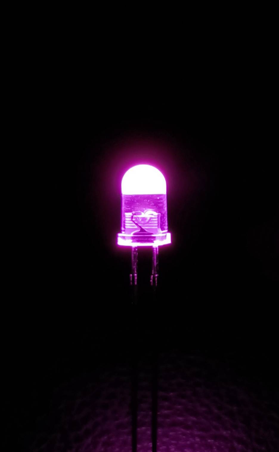 Eine leuchtende pinke LED-Lampe vor schwarzem Hintergrund, symbolisiert Energieeinsparung und moderne Beleuchtungstechnologie.