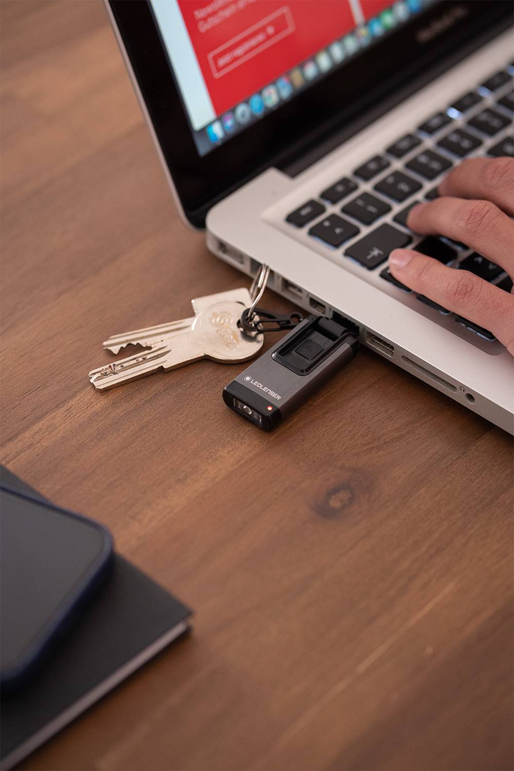 Eine Hand verwendet ein Notebook mit einem angeschlossenen USB-Stick zusammen mit einem Schlüsselbund.