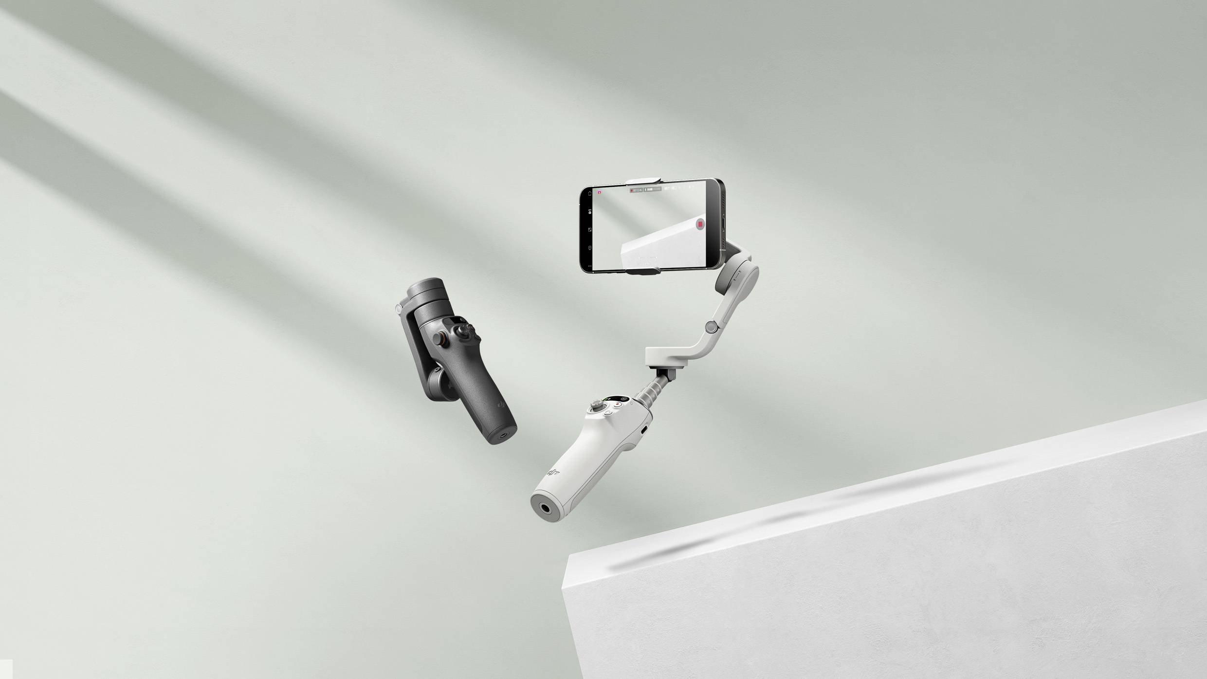 Ein Smartphone-Gimbal schwebt vor einem hellen Hintergrund, zeigt Bewegungsfreiheit. Ein Smartphone ist darin eingeklemmt.