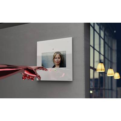 Ein hell erleuchteter Raum mit großem Fenster im Hintergrund. An der Wand hängt ein digitales Display mit dem Bild einer Frau. Ein rotes Objekt ist im Vordergrund sichtbar.