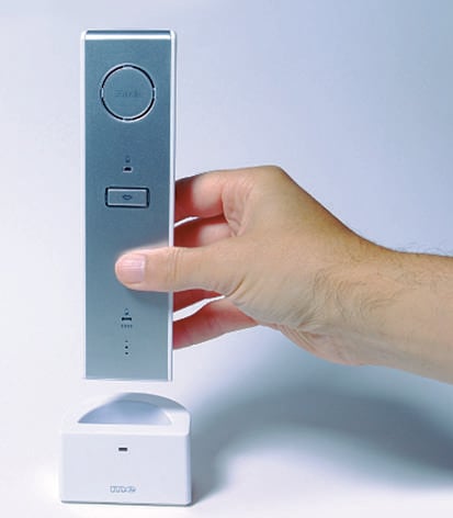 Eine Hand hebt einen modernen, schlanken, silbernen Telefonhörer von einer weißen Basisstation ab.