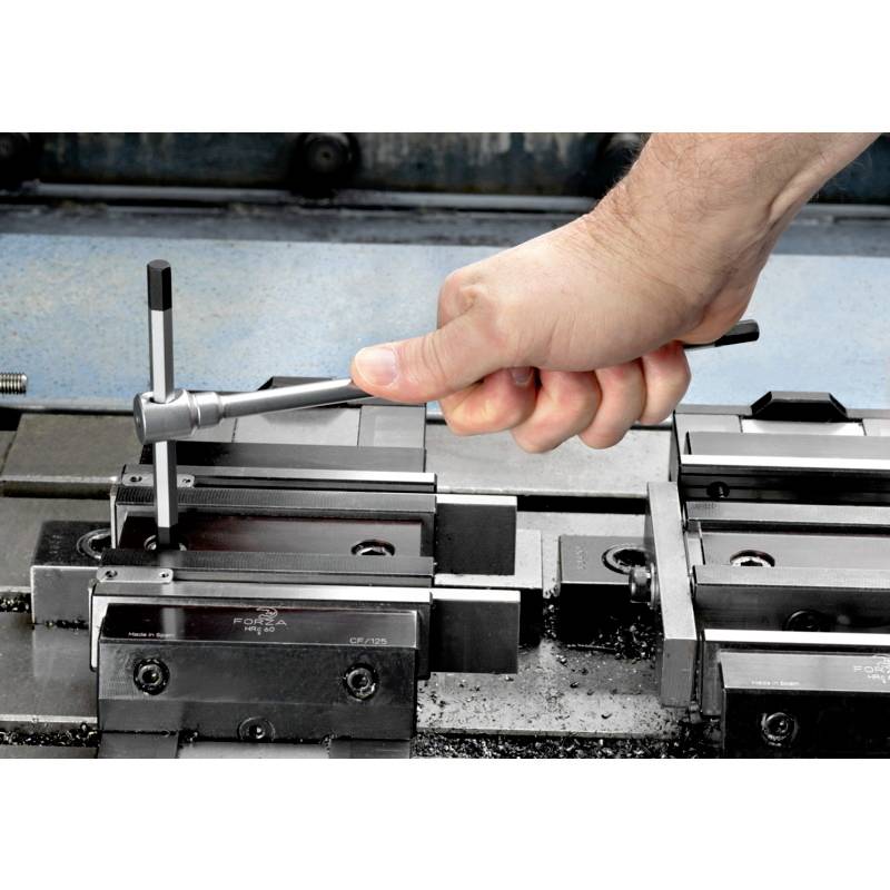 Eine Hand justiert mit einem Schraubenschlüssel den Schraubstock an einer Werkbank, um ein Metallstück zu fixieren.